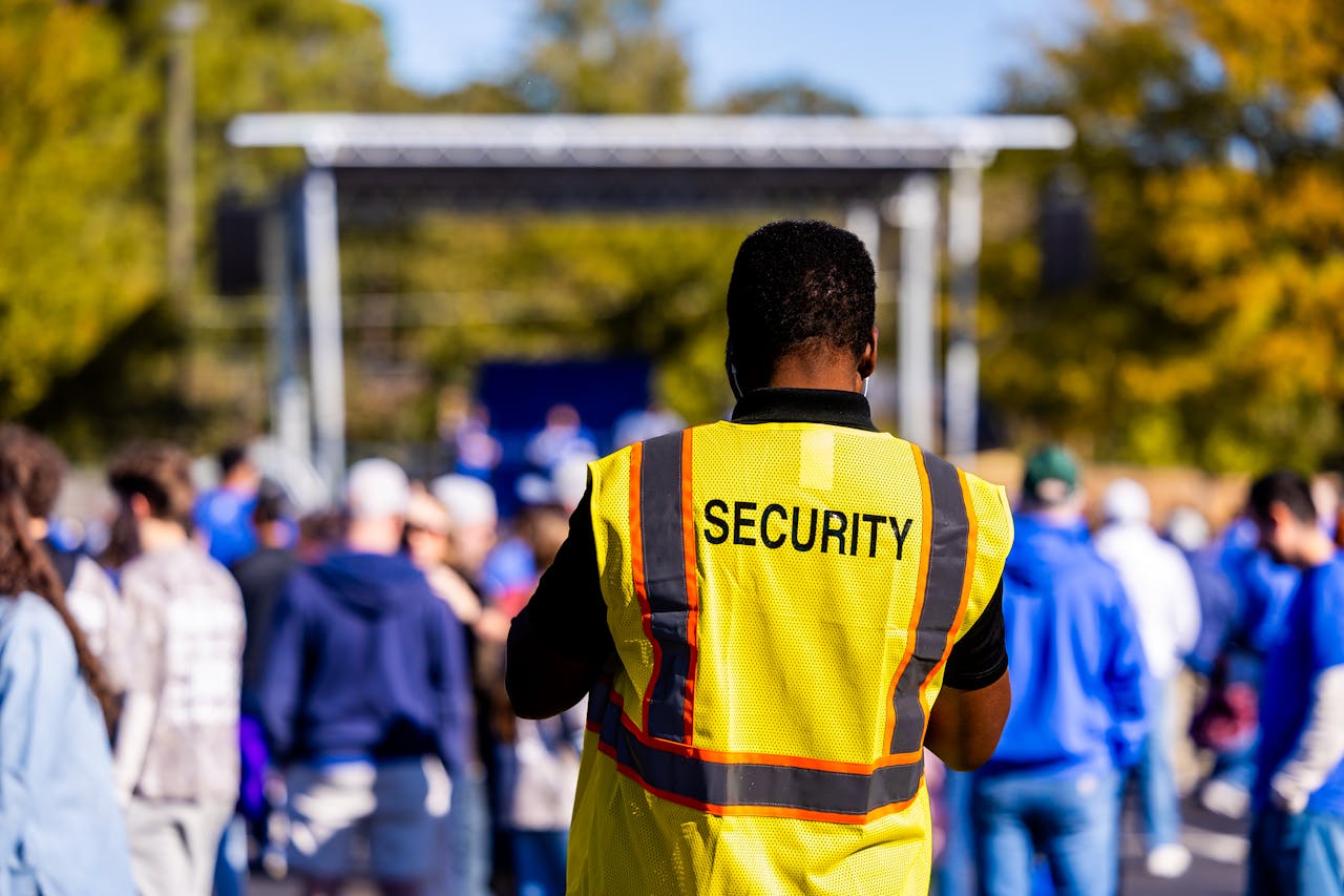 A security guard monitors a crowd at an outdoor event, ensuring safety and order.